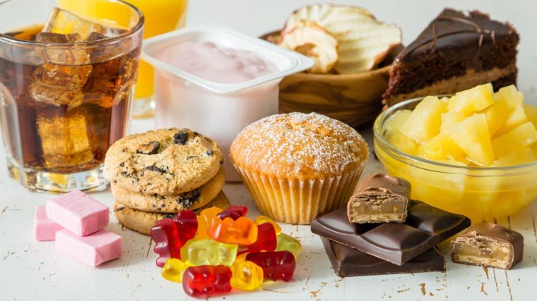 a selection of sugary food including sweets, fruit, fizzy drink and cake