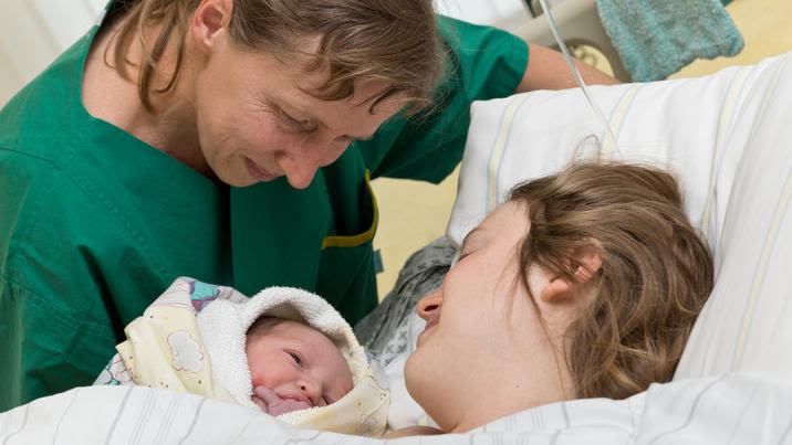 Midwife, woman and her newborn baby